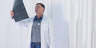 医生在看放射照片的肖像。年长的教授看着分析在白人现代诊所