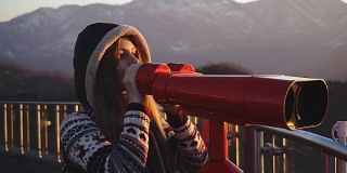 游客通过投币双筒望远镜看城市日落，中镜头