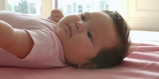 小女孩躺在粉色毯子上的慢动作镜头