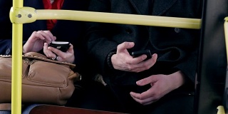 一对年轻夫妇一起坐在公交车上玩智能手机