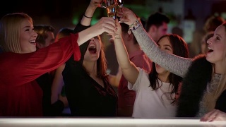 四个迷人的女孩在俱乐部的酒吧举起他们的香槟杯视频素材模板下载