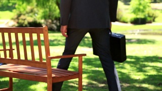 商人坐在公园的长椅上视频素材模板下载