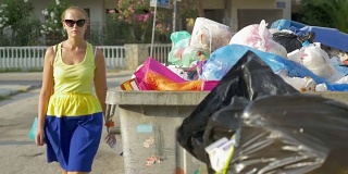 女人把塑料瓶扔进街道垃圾里