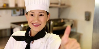 快乐的厨师对着镜头微笑，竖起大拇指