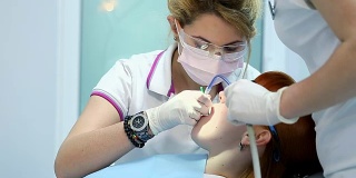 一位牙医给一位年轻的女病人钻孔