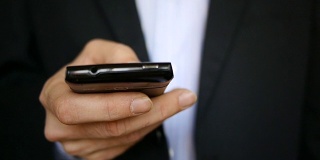 Close up footage of male businessman, texting, browsing internet on smartphone
