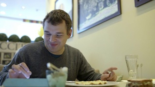 一个拿着触摸板的人在咖啡馆里吃饭视频素材模板下载