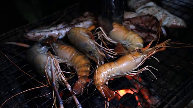 把虾和鱿鱼放在火焰烤架上。海鲜烧烤