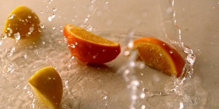 橙色和柠檬片落在潮湿的白色表面