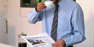 生意人一边看报纸一边喝咖啡