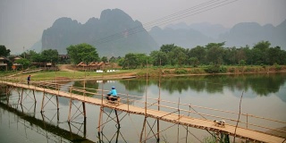 人们通过竹桥在石灰石山的背景