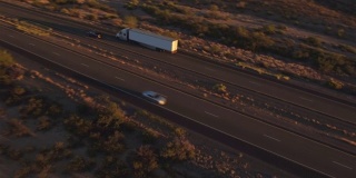 图片:夏日日落时分，汽车和半卡车在繁忙的高速公路上行驶