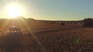 图片:金色的夏日夕阳下，一辆黑色SUV行驶在空旷的乡村道路上视频素材模板下载