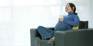 坐在沙发上的亚洲孕妇