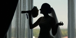 窗边新娘的剪影和她的婚礼花束