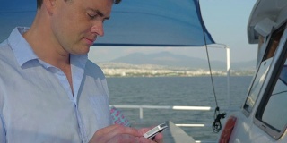 在游艇上用智能手机的男人