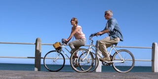 一对老夫妇在码头上骑自行车