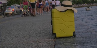 手提箱上戴着夏天的帽子，它在拥挤的海滨