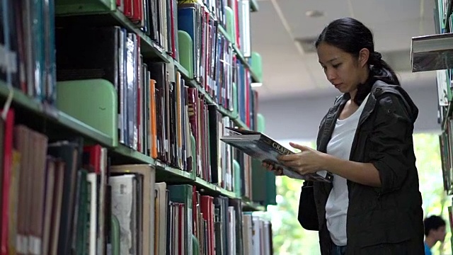 女，亚洲女学生站在书架上找书，看书