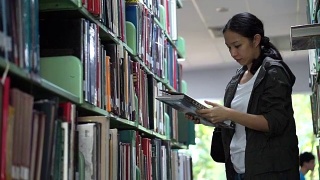 女，亚洲女学生站在书架上找书，看书视频素材模板下载