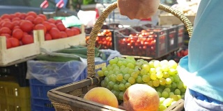 在水果市场上，挎着一篮葡萄和桃子的人