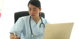 亚洲医生在电脑上分析医疗结果并做笔记