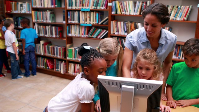 学生和老师在图书馆看电脑
