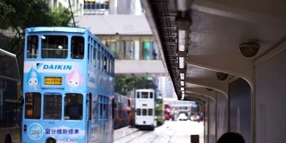 标志性的香港有轨电车概念。人们在电车站等候，后面有一辆车驶近