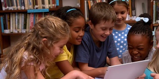 可爱的学生在图书馆看笔记本电脑