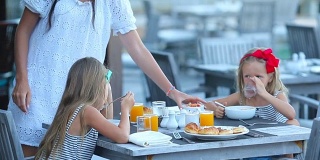 可爱的小女孩在户外咖啡厅吃早餐