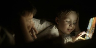 两个男孩晚上躺在床上用垫子