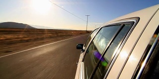 在废弃的高速公路上行驶的汽车侧面安装了摄像头。汽车在沙漠道路上行驶的POV。车右转