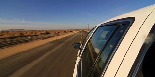Camera attached on the side of the car driving on deserted highway. POV of car driving on desert road. Car turning right