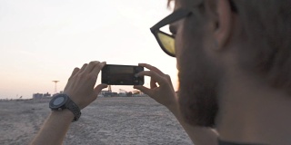 模特在海滩发布了智能手机摄影师