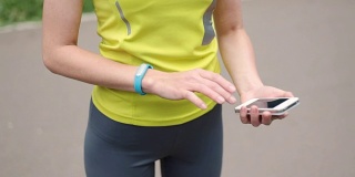 女人的手与运动手镯和智能手机