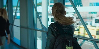 一个背着背包的女孩走在机场的走廊上