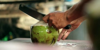 一个男人用一把大刀切开椰子。