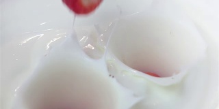 两段草莓落入酸奶的视频，慢镜头