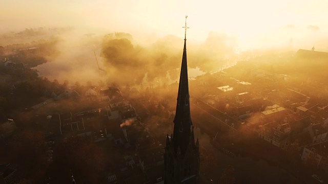 镜头倾斜，显示一个十字架在一个基督教教堂的顶部被雾覆盖