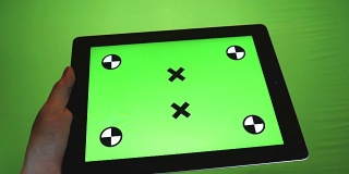 在绿色背景下使用绿色屏幕的平板电脑的人
