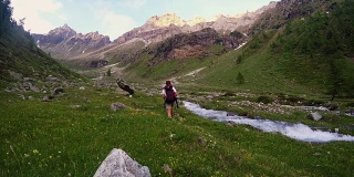 背包客在田园诗般的风景中徒步旅行。夏季冒险和探索在阿尔卑斯山，通过盛开的草地和绿色林地设置在高海拔山脉。瓦莱达奥斯塔,意大利。
