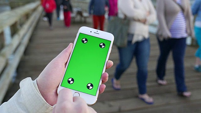 女人拿着绿色屏幕显示手机用手指手势