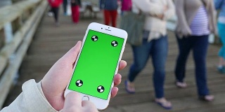 女人拿着绿色屏幕显示手机用手指手势