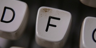 用手指在老式打字机上敲字母F。