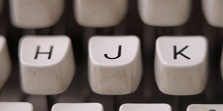 用手指在老式打字机上敲字母J。