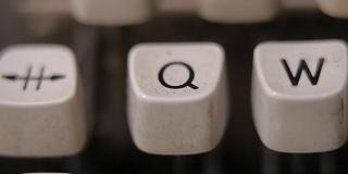 用手指在老式老式打字机上敲字母Q。