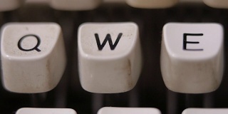 男性用手指在老式老式打字机上敲字母W。