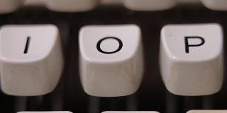 男性用手指在老式老式打字机上敲字母O。
