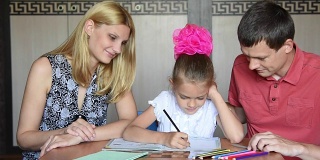 女学生和父母一起做作业微笑着看着相框
