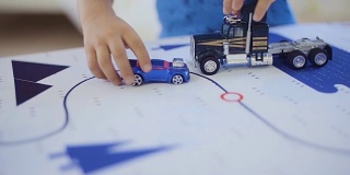 小男孩在彩色的桌子上玩玩具卡车